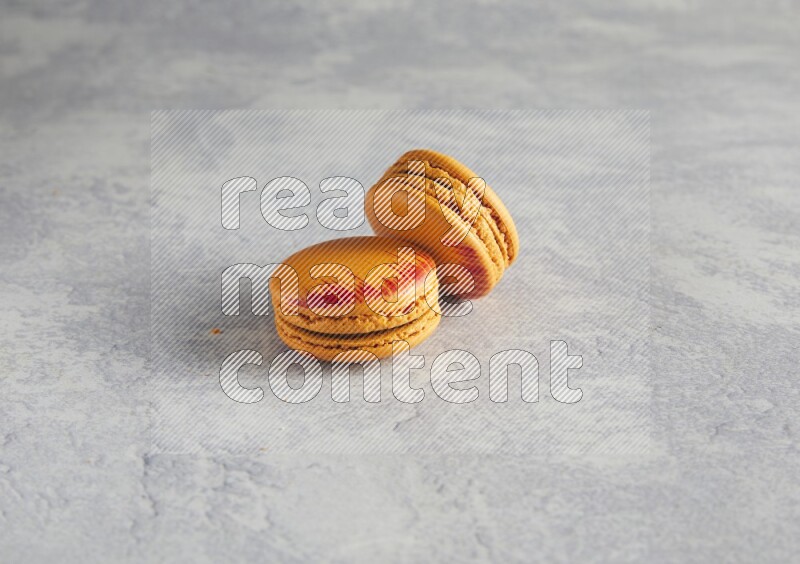 45º Shot of two orange Exotic macarons on white  marble background