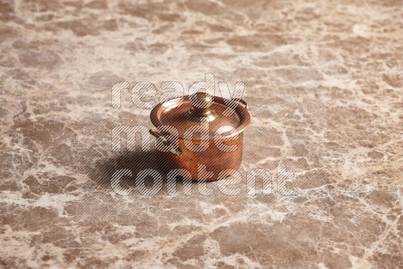 A small copper pot on beige marble background
