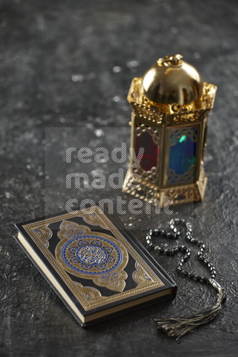 A golden lantern with different drinks, dates, nuts, prayer beads and quran on textured black background