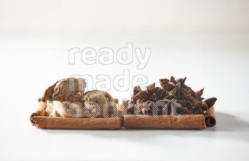 مربعان من أعواد القرفة ممتلئان باليانسون النجمي والزنجبيل المجفف علي خلفية بيضاء