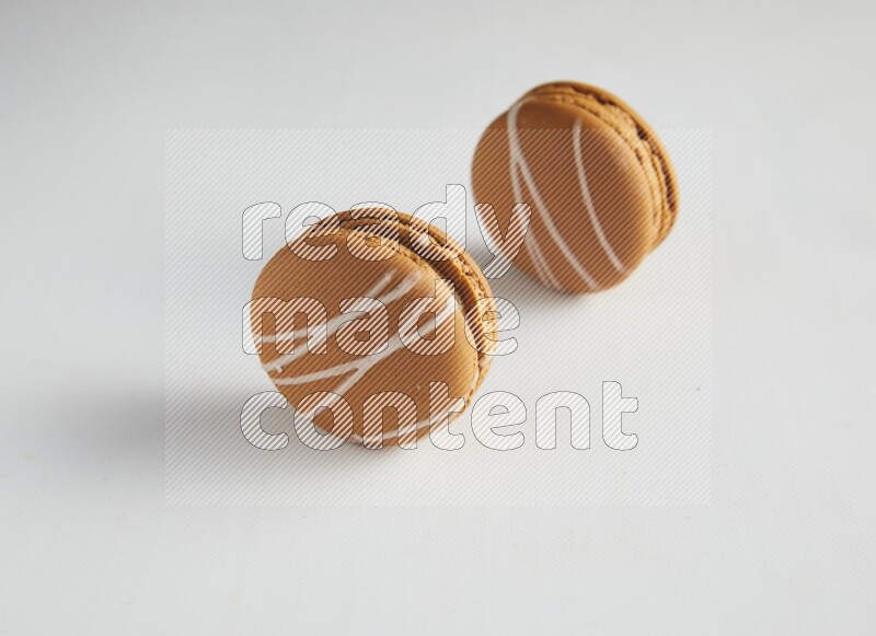45º Shot of two Brown Irish Cream macarons on white background