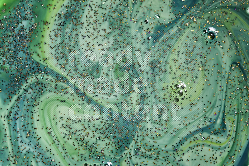 A close-up of sparkling gold glitter scattered on swirling green background