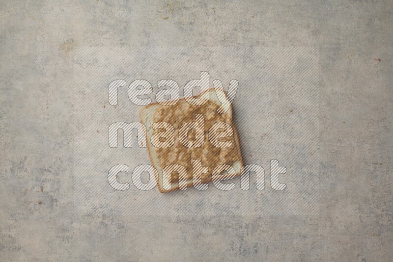 Crunchy peanut butter on a white toast on a light blue textured background