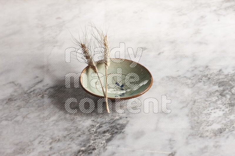 Wheat stalks on decorative pottery plate on grey marble background