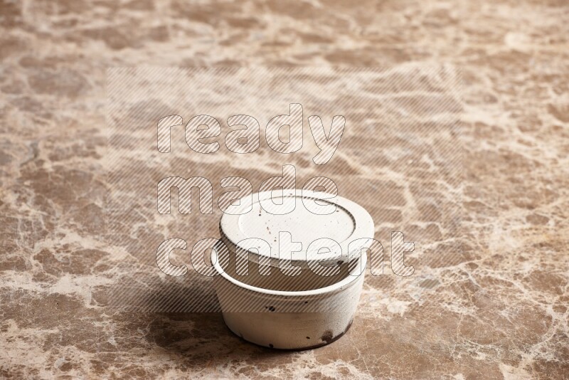 A white pottery bowl on beige marble background
