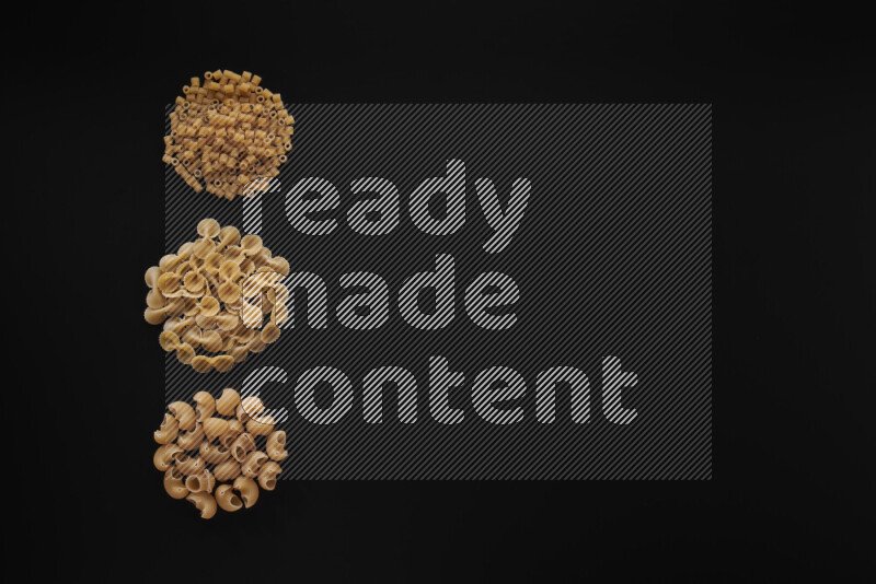 Different pasta types in 3 bunches on black background