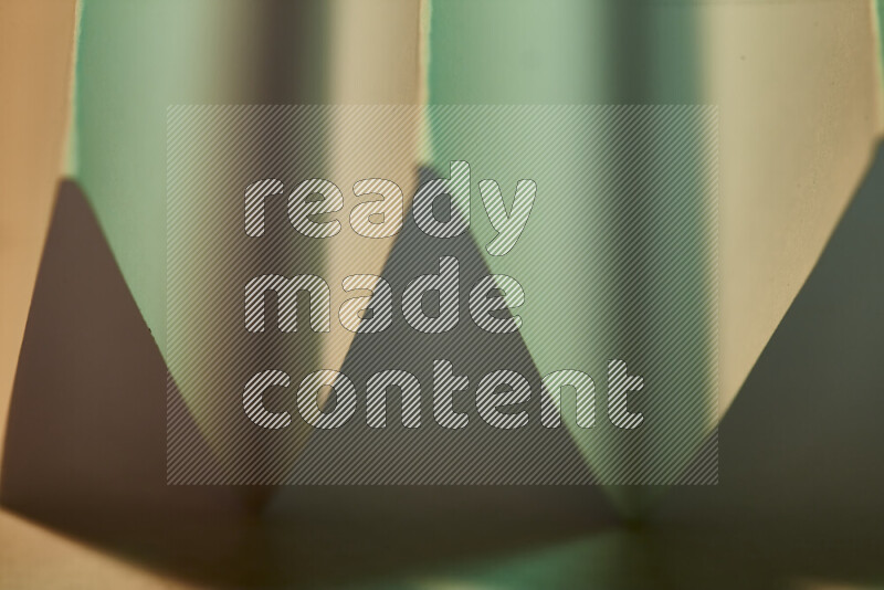 صورة مجردة مقربة تظهر طيات ورقية هندسية حادة بتدرجات اللون الأخضر مع درجات لونية دافئة