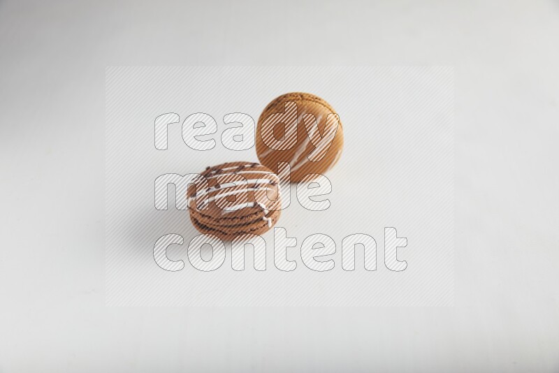 45º Shot of of two assorted Brown Irish Cream, and Brown white Chocolate Caramel macarons on white background