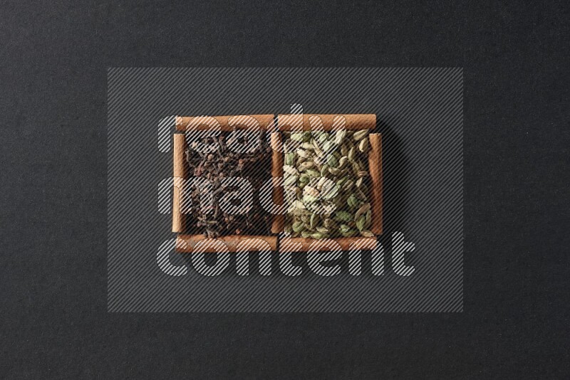 2 squares of cinnamon sticks full of cardamom and cloves on black flooring