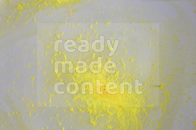 The image captures a dramatic splatter of yellow paint over a white backdrop