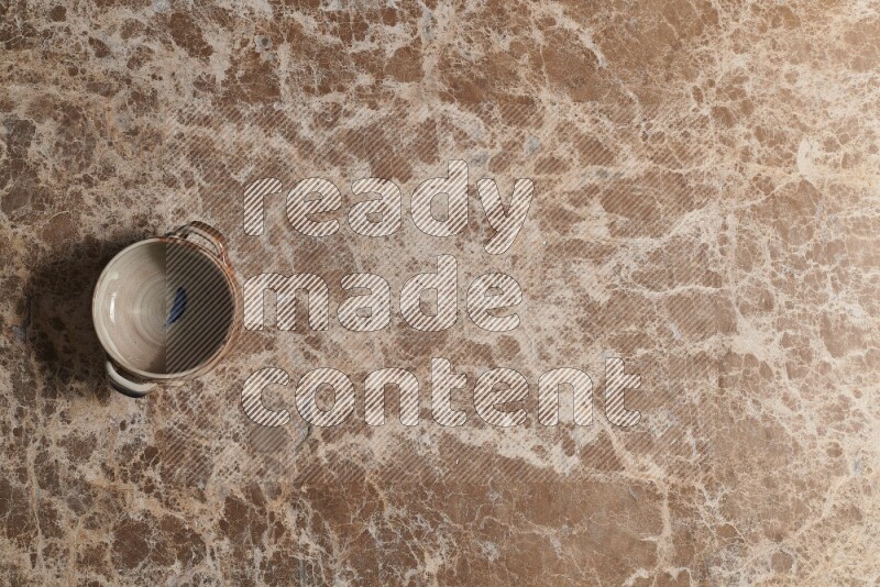 A multicolored pottery bowl on beige marble background