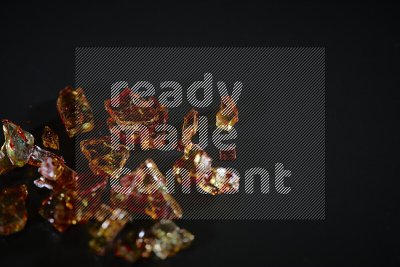 قطع زجاج برتقالية شفافة متناثرة على خلفية سوداء