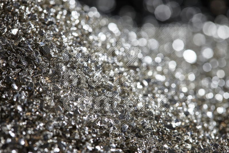 Silver shimmering fragments of glass scattered on a black background