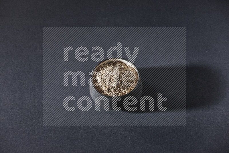 Black pottery bowl full of white pepper on black flooring