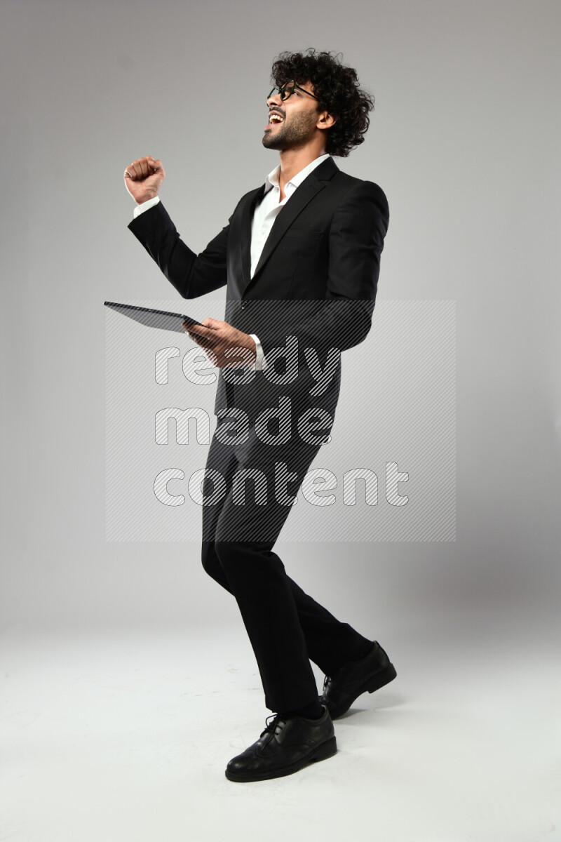 A man wearing formal standing and gaming on a tablet on white background