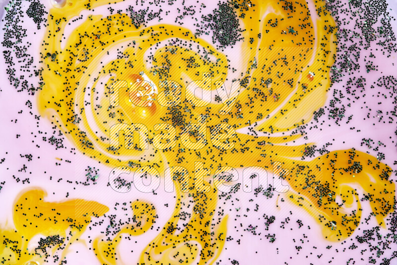 لقطة مقربة لبريق أخضر متلألئ منتشر على خلفية من اللون الأصفر والوردي في حركات دائرية