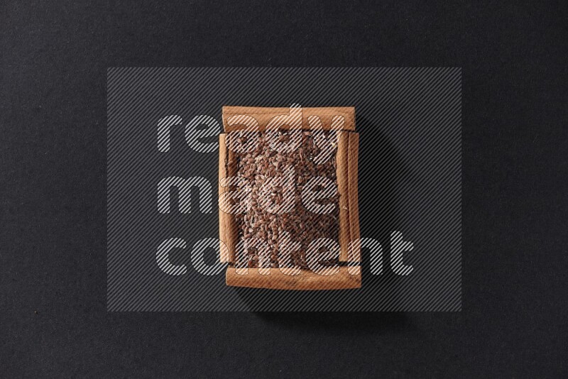 A single square of cinnamon sticks full of flaxseeds on black flooring