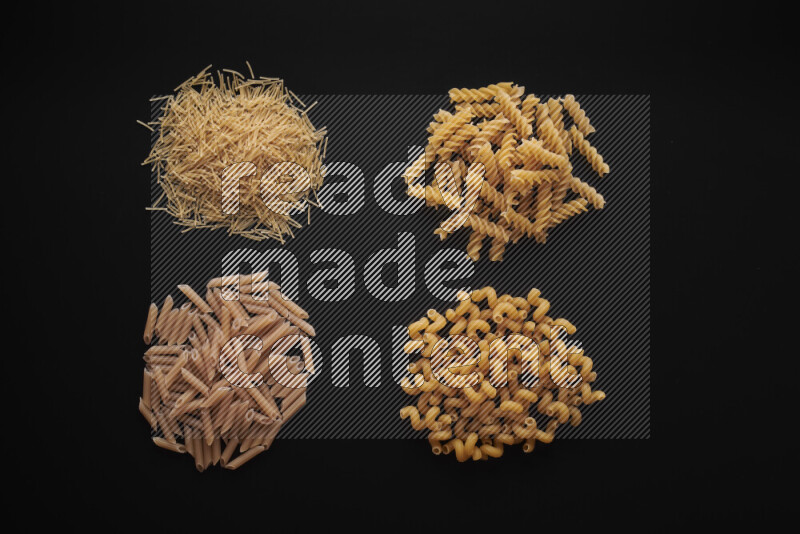 Different pasta types in bunches on black background