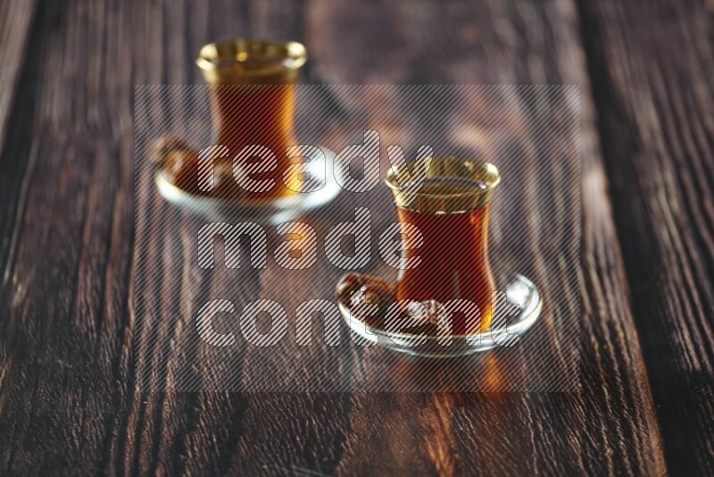 A tea glass cup with dates and coffee on wooden background