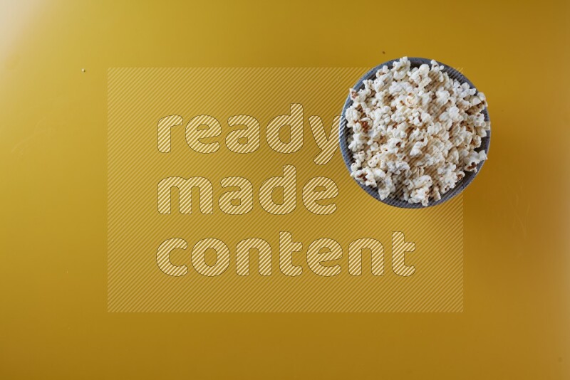 A multicolored pottery bowl full of popcorn on a yellow background in different angles