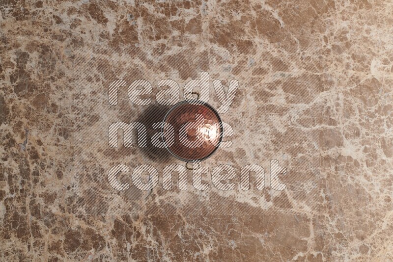 A small copper pot on beige marble background