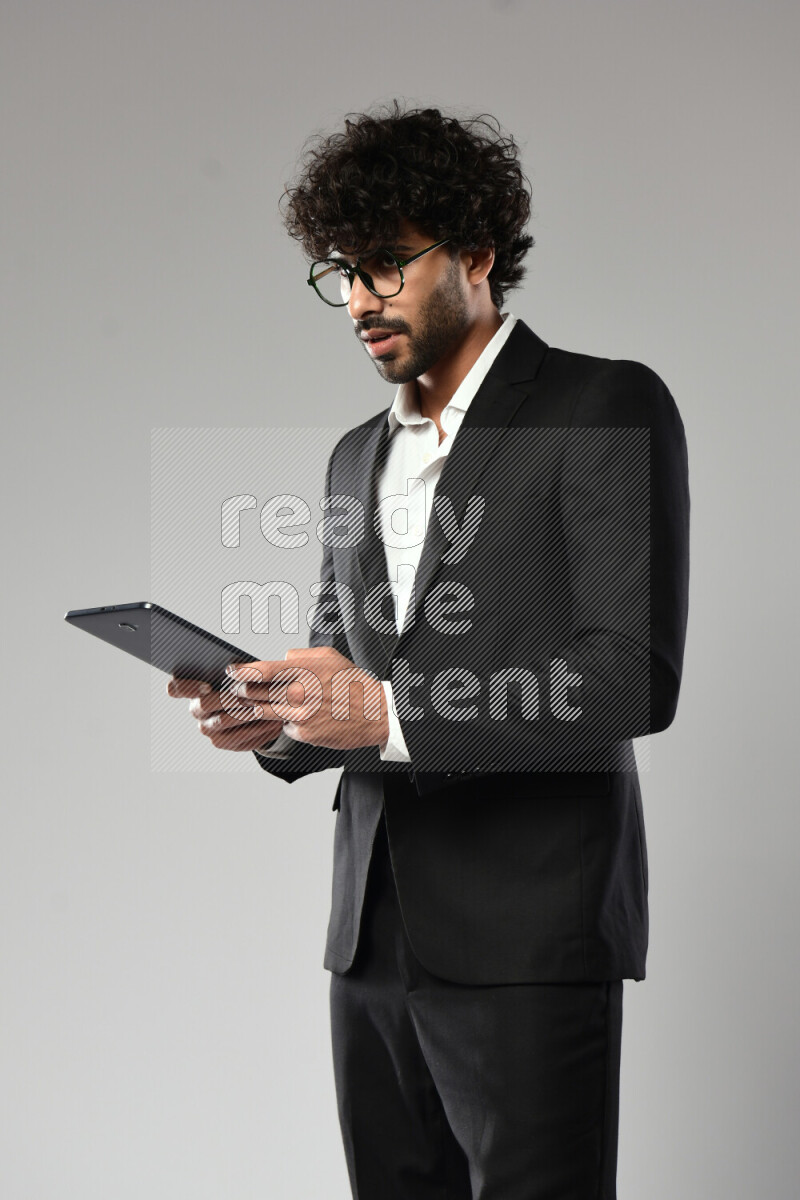 A man wearing formal standing and browsing on a tablet on white background