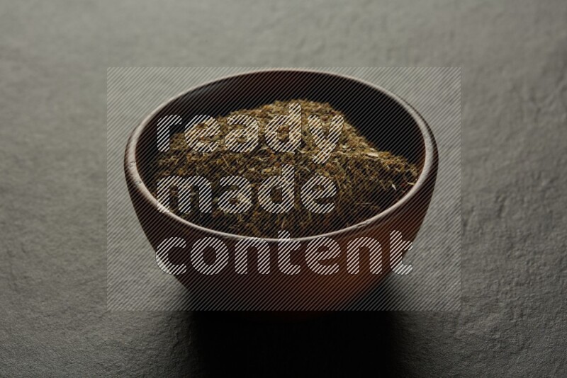 wooden round sauce bowl filled with herbs on grey textured countertop