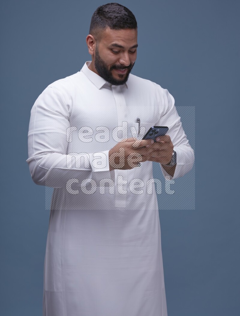 A man Texting on Blue Background wearing Saudi Thob