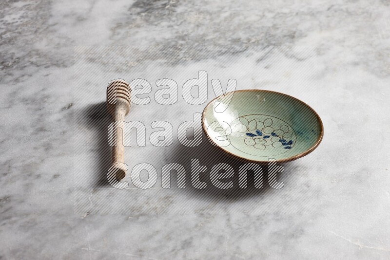 Decorative pottery plate with wooden honey dipper on the side on grey marble background
