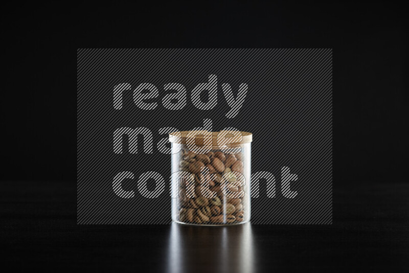 Fava beans in a glass jar on black background