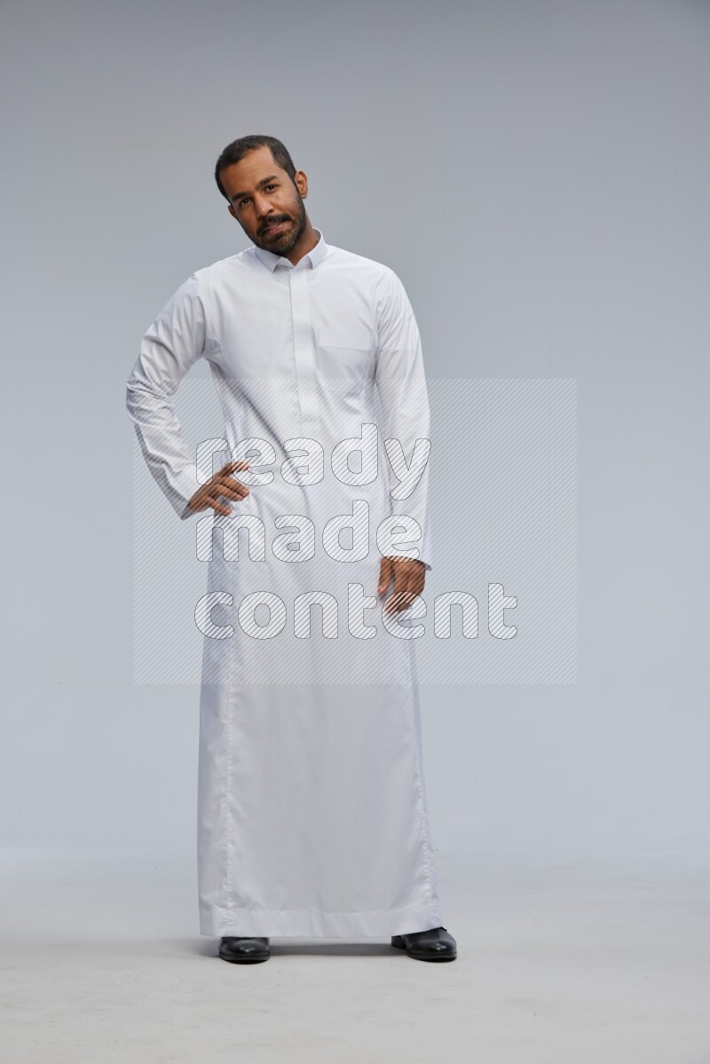 Saudi man Wearing Thob standing interacting with the camera on Gray background