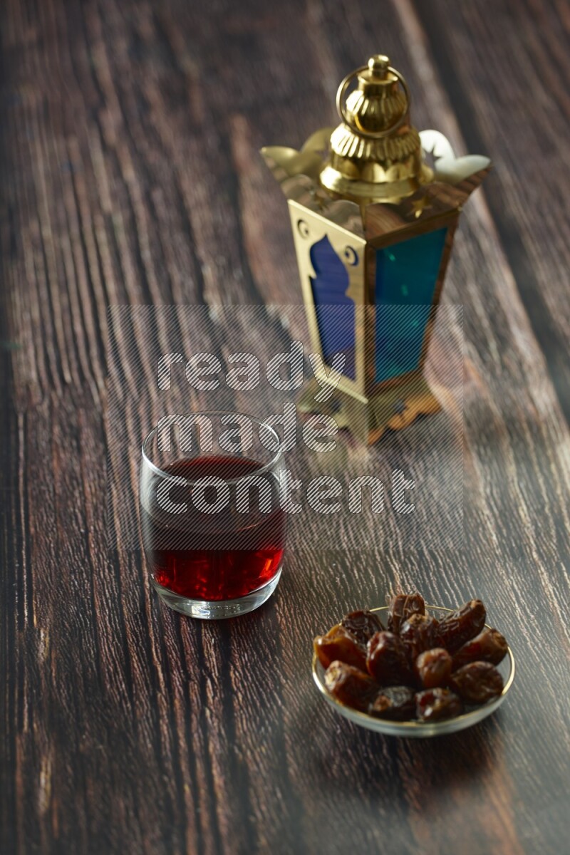 A golden lantern with different drinks, dates, nuts, prayer beads and quran on brown wooden background