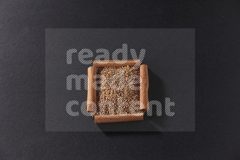 أربعة من أعواد القرفة مكونة شكل مربع بداخلها حبوب الخردل علي خلفية سوداء