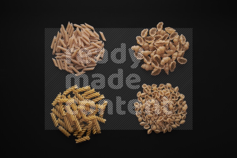 Different pasta types in bunches on black background