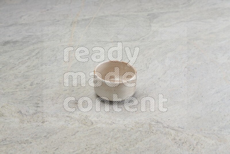 A small beige pottery bowl on grey marble background