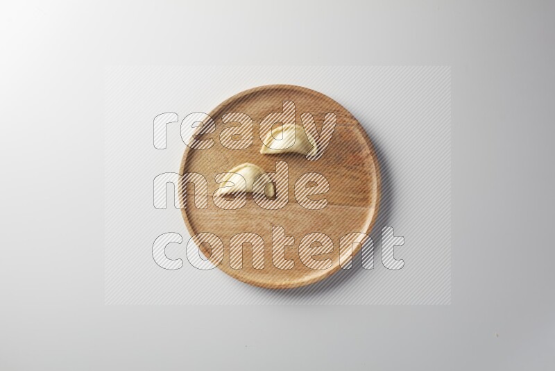 Two Sambosas on a wooden round plate on a white background