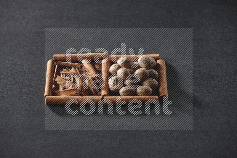 2 squares of cinnamon sticks full of cinnamon and nutmeg on black flooring