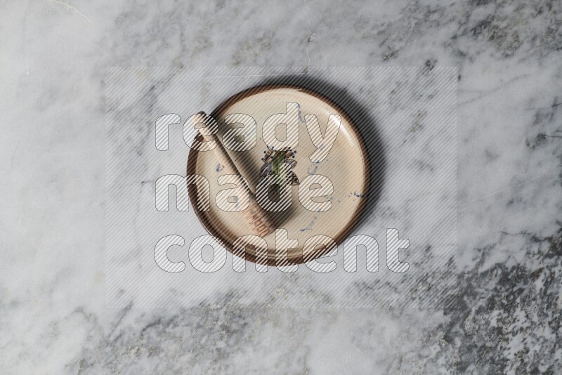 Decorative pottery plate with wooden honey dipper in it on grey marble background