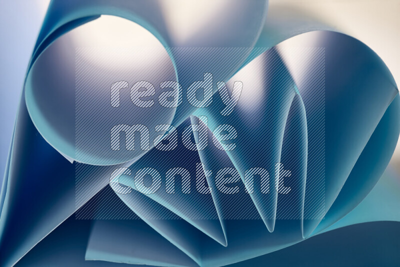 An artistic display of paper folds creating a harmonious blend of geometric shapes, highlighted by soft lighting in blue tones
