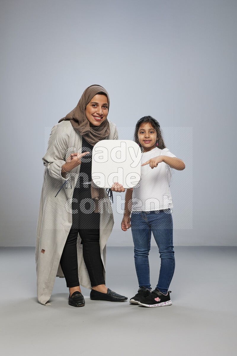 Mom and daughter standing holding social media sign on gray background