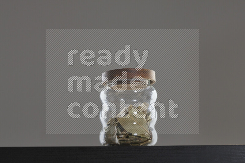 Bay laurel leaves in a glass jar on black background