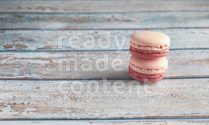 45º Shot of two Pink Litchi Raspberry macarons on light blue wooden background