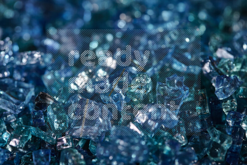Transparent blue fragments of glass scattered on a black background