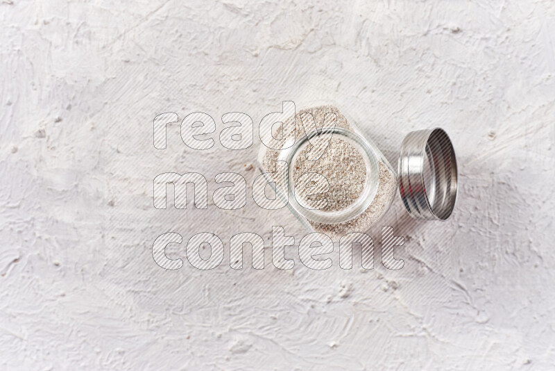 A glass jar full of onion powder on white background