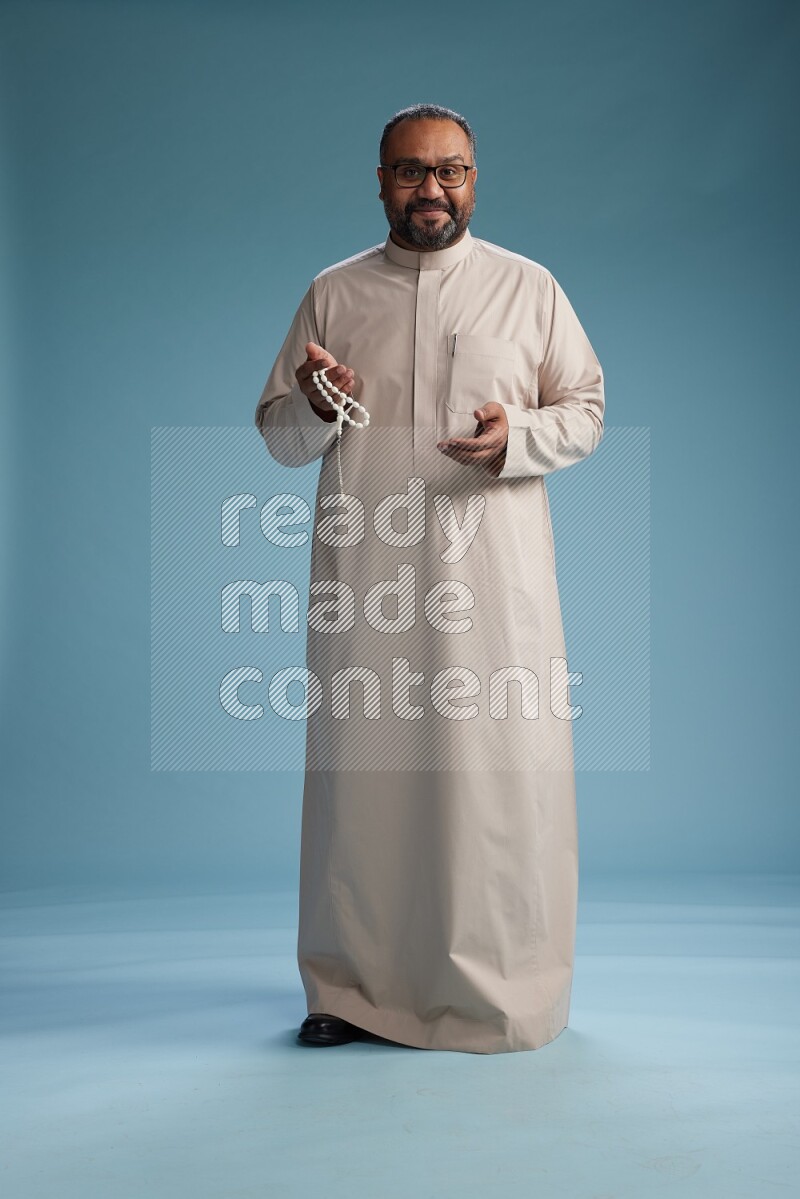 Saudi Man without shimag Standing Interacting with the camera on blue background