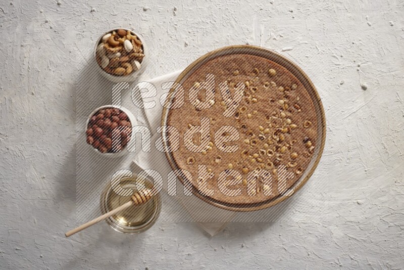 البسبوسة مع المكسرات والعسل علي خلفية بيضاء خشبية