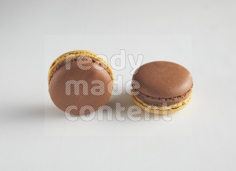 45º Shot of two Yellow and Brown Chai Latte macarons on white background