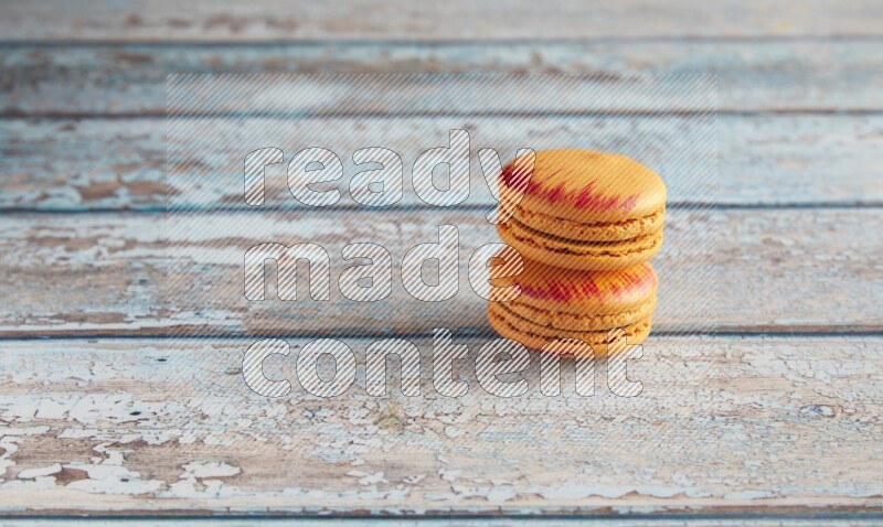 45º Shot of two orange Exotic macarons on light blue wooden background
