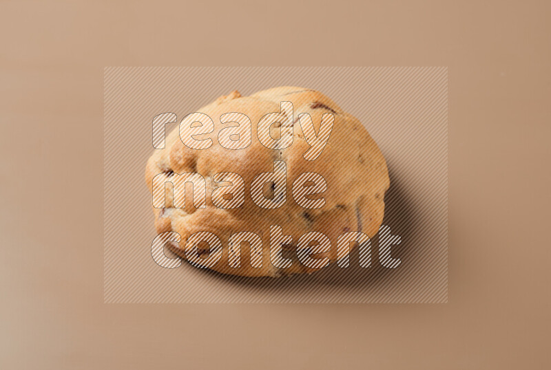a whole chocolate chip cookie on a brown background