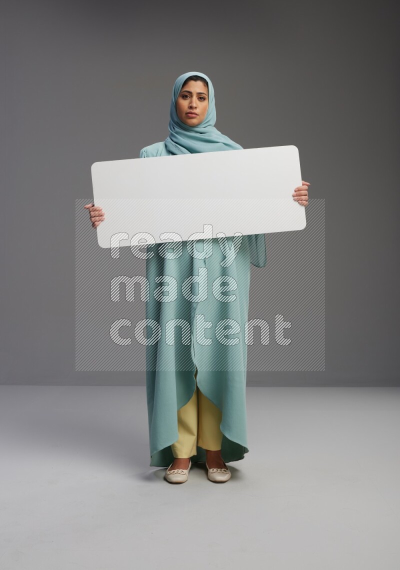 Saudi Woman wearing Abaya standing holding board on Gray background